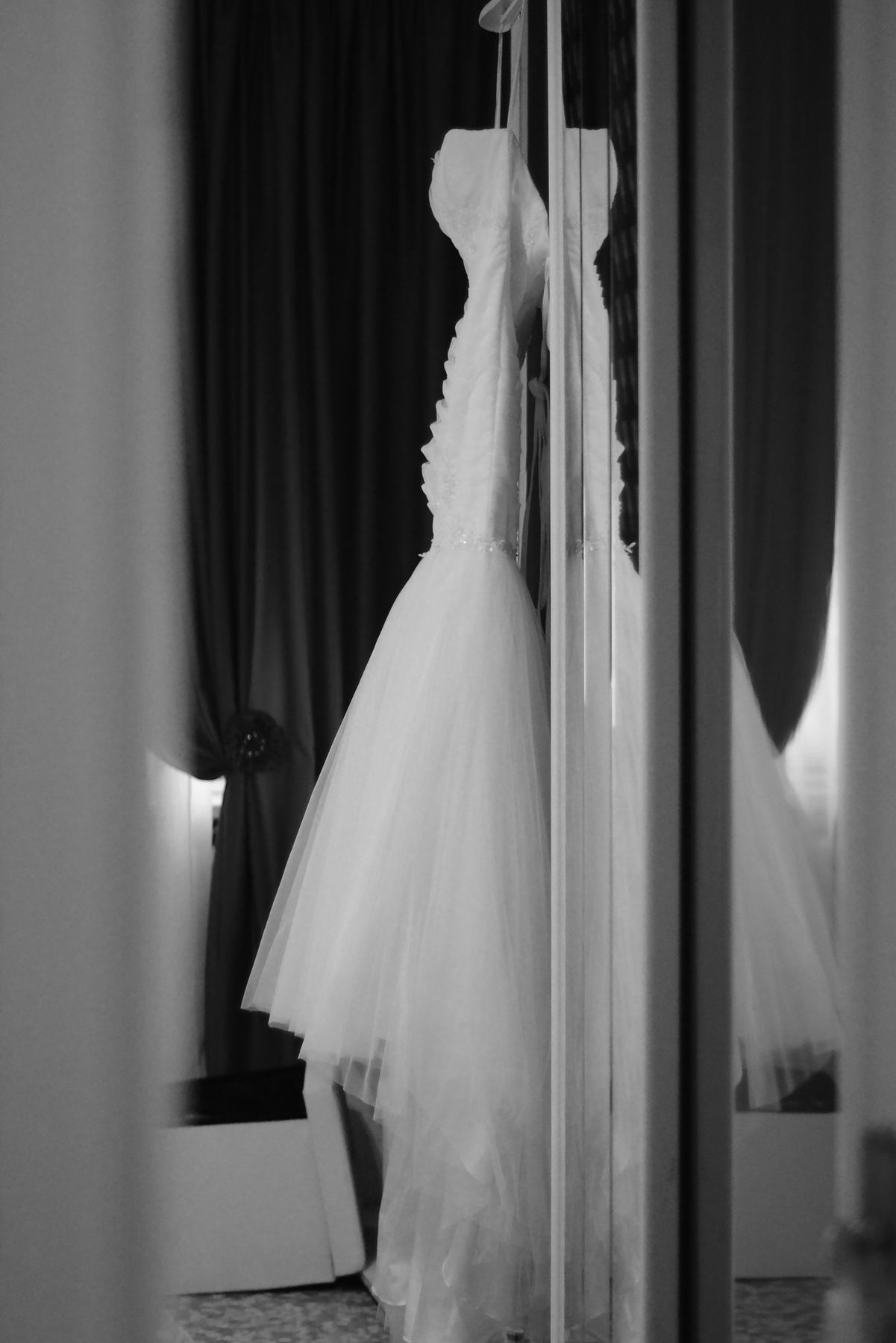 Un vestido de novia colgado frente a un espejo